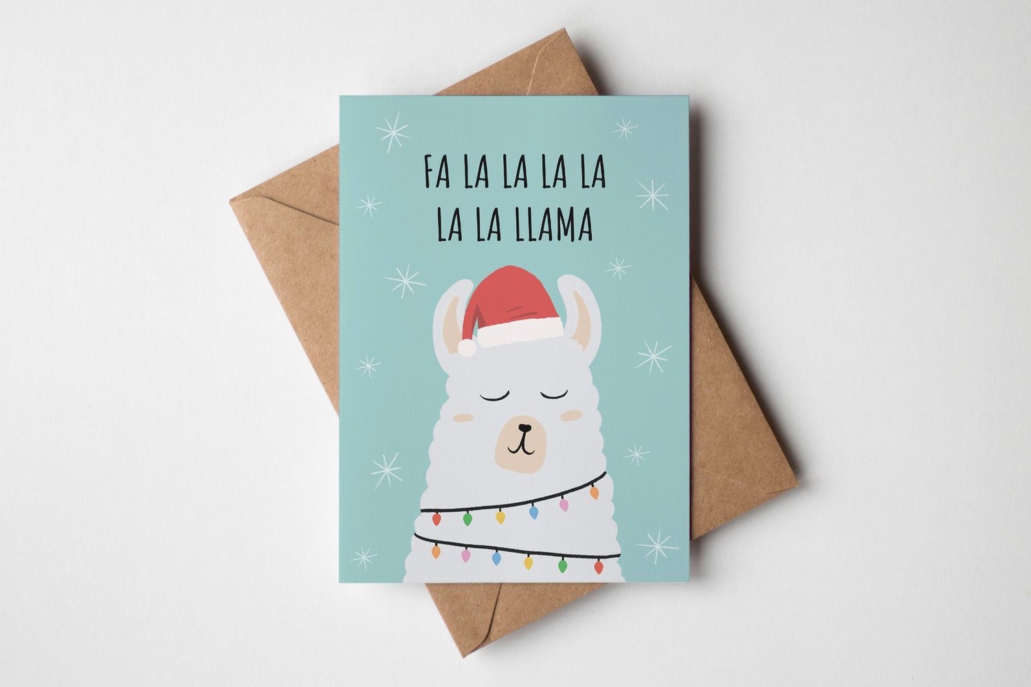 Christmas card with a llama illustration and 'Fa La La La Llama' text on a light blue background.