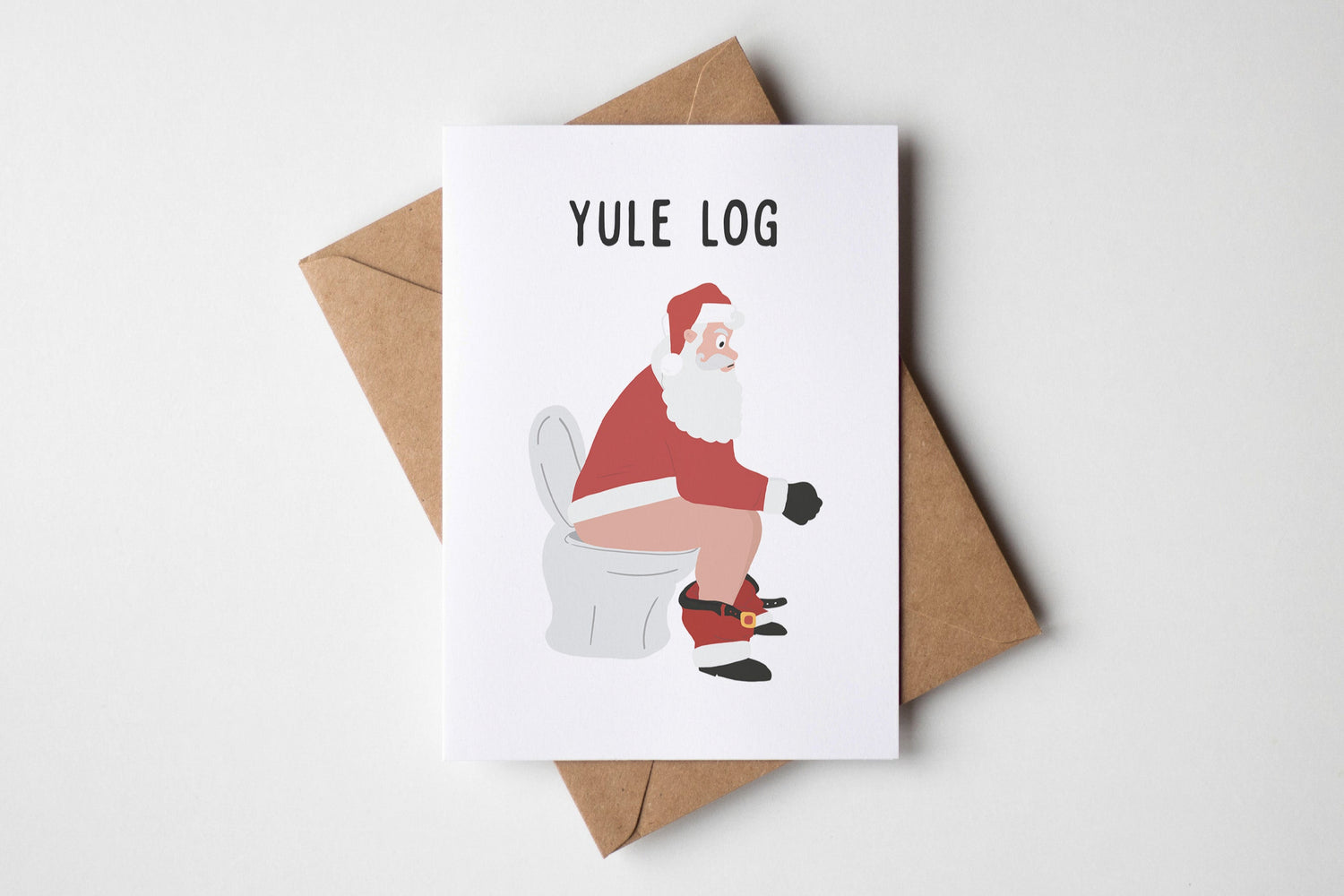 Card with Santa Claus on a toilet and 'Yule Log' text, with a brown envelope.